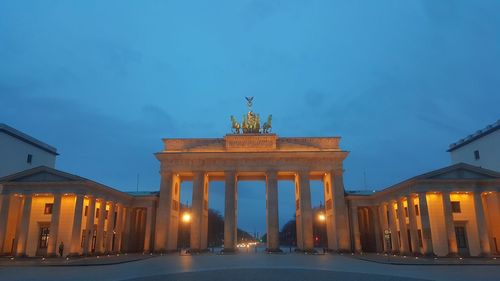 Statue in city against sky at night