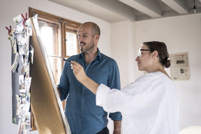 Business people discussing while standing by canvas fabric at office