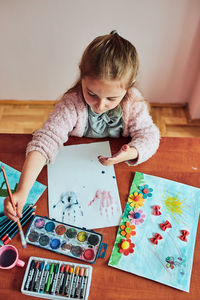High angle view of girl painting on paper