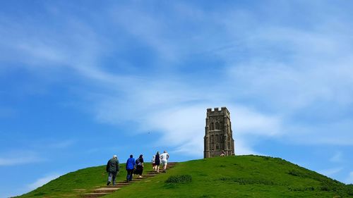 Rear view of people at st michael tower on glastonbury against sky