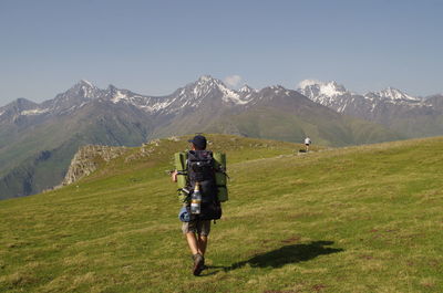 Rear view of friends walking on mountain against sky