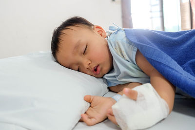 Injured boy sleeping on bed at home