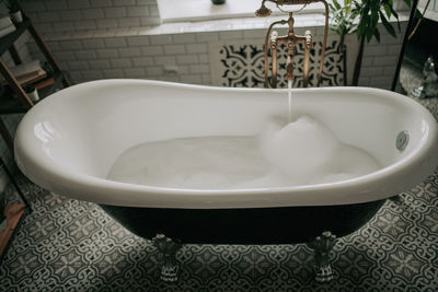 Luxury interior of big bathroom at modern african style with oval bathtub in natural lighting