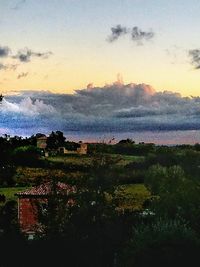 Scenic view of trees and buildings against sky during sunset