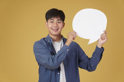 Portrait of a smiling young man against yellow background