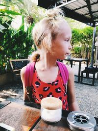 Cute girl looking away while standing by table