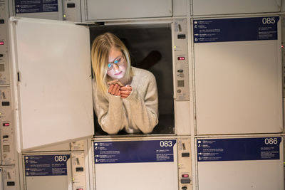 Young woman using phone in locker