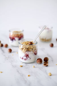 Oatmeal granola with greek yogurt and nuts strawberry muesli in jars on light background