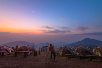 People standing on mountain against sky during sunset