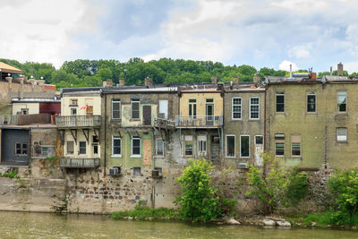 Residential buildings by river against sky
