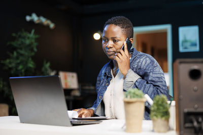 Young woman using mobile phone while sitting on table