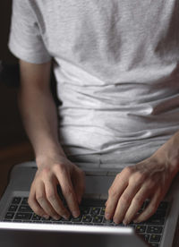 Hands of a young caucasian man typing with his fingers on the keyboard doing onlin shopping.