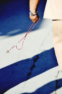 Midsection of man with rosary walking on road