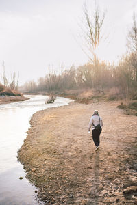 Rear view of man walking on shore against sky