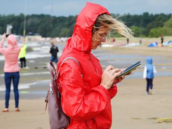 Midsection of woman holding mobile phone while standing on land