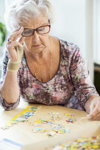 Senior woman solving jigsaw puzzle at table in nursing home