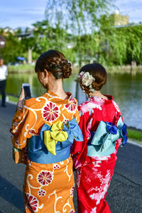 Rear view of young woman standing by lake