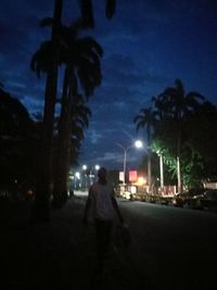 Woman walking on road in city at night