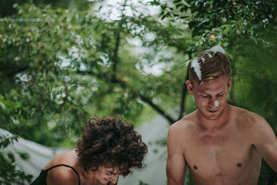 Portrait of shirtless young man against trees