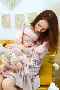 Beautiful young mother is holding her little daughter in hands. candid family portrait.