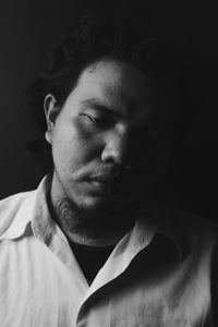 Close-up of sad young man against black background