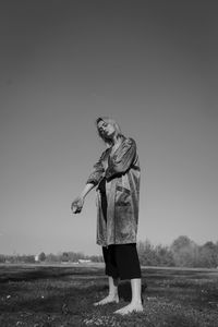 Portrait of woman with apple standing on field against clear sky