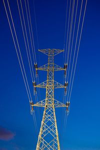 Low angle view of electricity pylon against blue sky