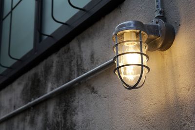 Low angle view of light bulb hanging against wall