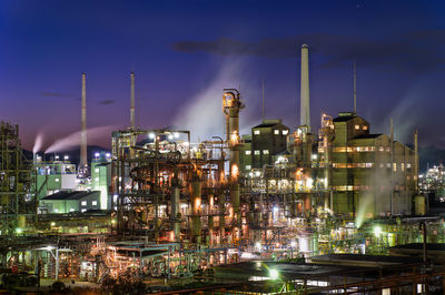 Illuminated factory against sky at night