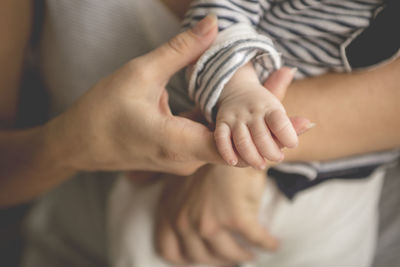 Cropped hands of mother holding newborn