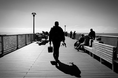 People walking on footbridge against sky