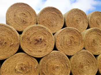 Stack of hay bales on landscape against sky