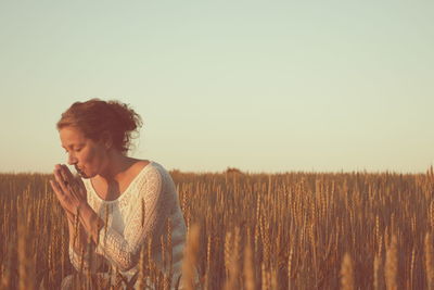Young woman standing on field against sky