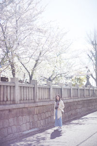 Full length of woman standing on footpath by plants