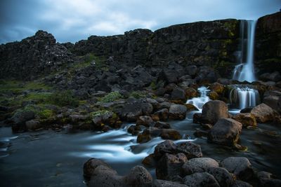 Water flowing through rocks against sky