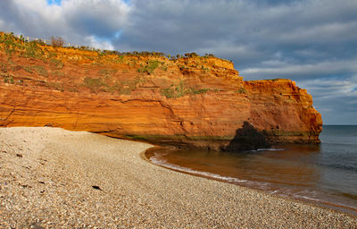 Rock formations on beach against sky