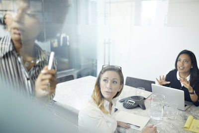 Female colleagues having discussion in office seen through window