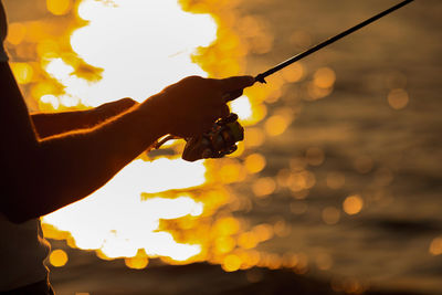 Cropped hand of man holding sparkler at night