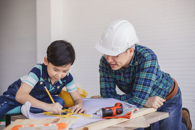 Engineer assisting son in making drawing