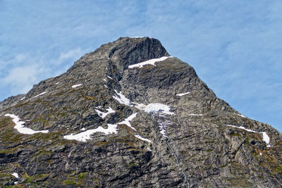 Rock formation on snow covered mountain against sky