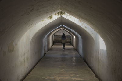 Rear view of woman walking in tunnel