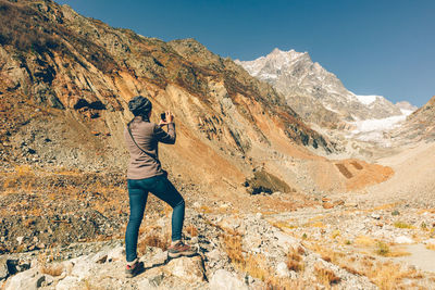 Rear view of woman photographing while standing on mountain