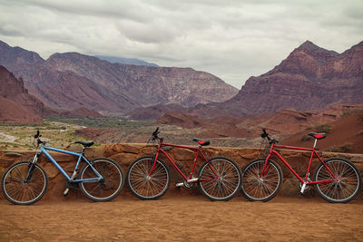 Bicycles leaning on retaining wall against mountains