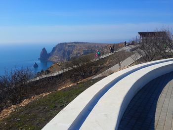 People on mountain by sea against sky