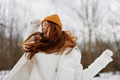 Cheerful woman wearing knit hat enjoying in snow