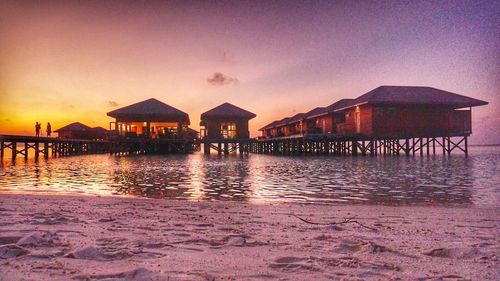 Built structure on beach against sky at sunset