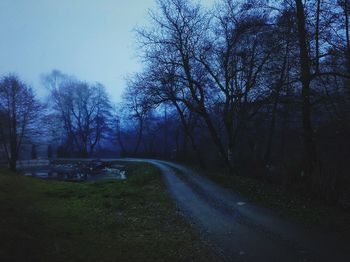 Road amidst trees on field against sky