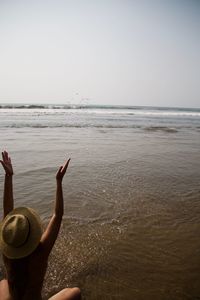 Rear view of woman with arms raised at beach