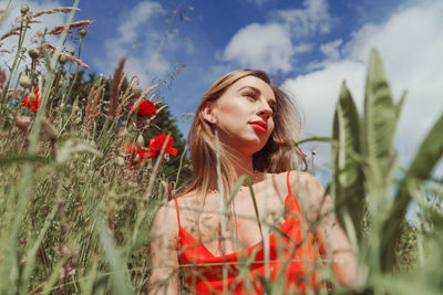 Portrait of young woman on field against sky