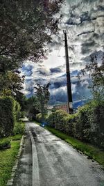 Footpath by sea against cloudy sky